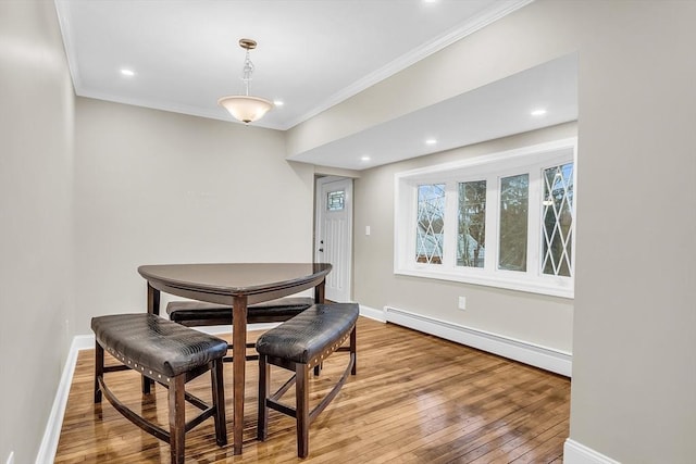 dining area with hardwood / wood-style flooring, baseboard heating, and ornamental molding