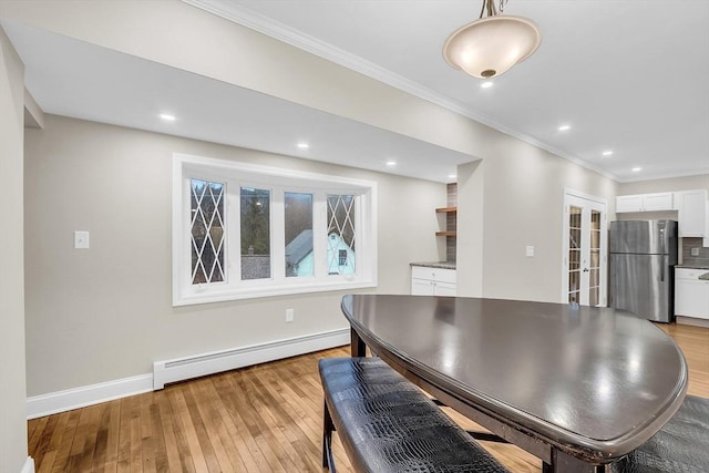 dining space featuring a baseboard radiator, light hardwood / wood-style flooring, and crown molding