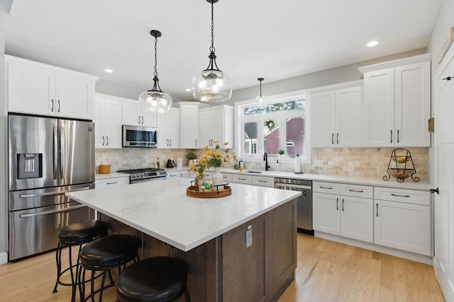 kitchen with light wood-style flooring, a kitchen island, white cabinetry, and stainless steel appliances