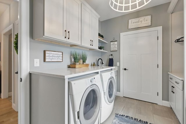 laundry room featuring baseboards, light wood-style floors, cabinet space, and washer and dryer