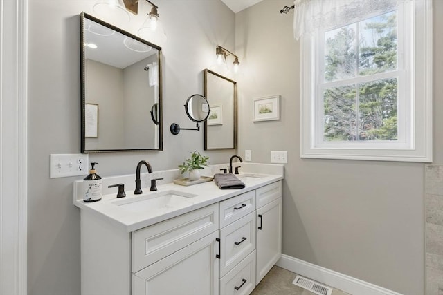 full bathroom with double vanity, baseboards, visible vents, and a sink