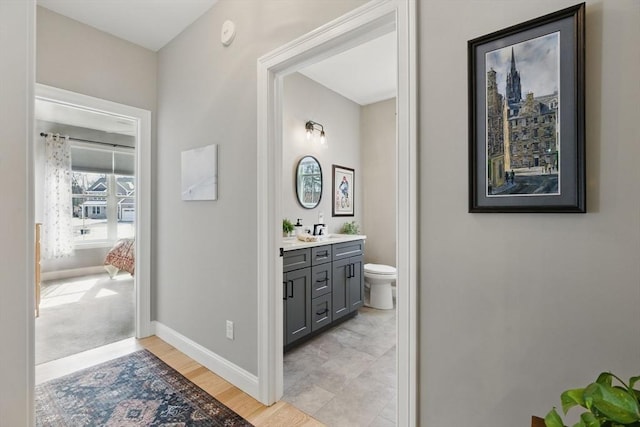 bathroom featuring toilet, baseboards, wood finished floors, and vanity