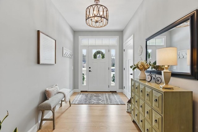 foyer featuring a notable chandelier, light wood finished floors, and baseboards