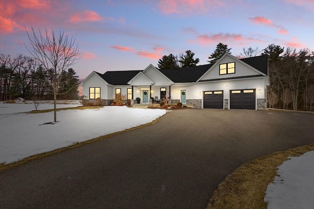 modern inspired farmhouse with a garage, driveway, and stone siding