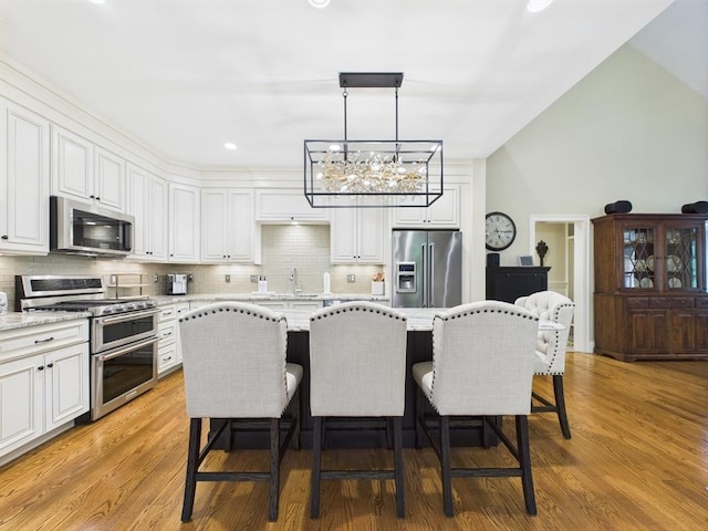20 Davenport Ln Unit 20, Hopkinton, MA 01748 - kitchen with stainless steel appliances, a chandelier, decorative backsplash, white cabinetry, and a breakfast bar area