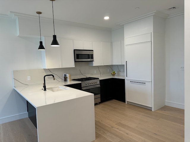 kitchen featuring stainless steel appliances, light hardwood / wood-style floors, white cabinetry, sink, and pendant lighting