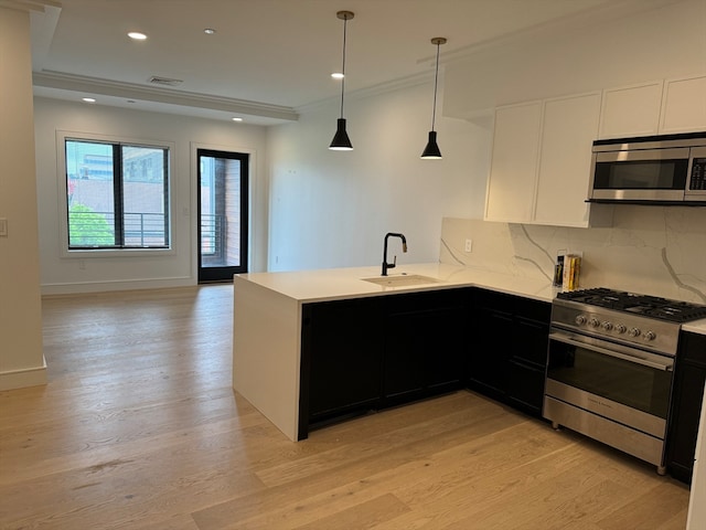 kitchen featuring appliances with stainless steel finishes, light hardwood / wood-style floors, white cabinetry, sink, and kitchen peninsula