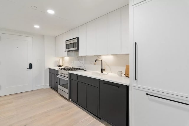 kitchen featuring stainless steel appliances, light hardwood / wood-style floors, white cabinetry, and sink