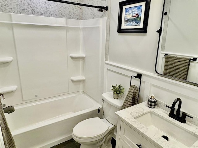 bathroom with a decorative wall, toilet, shower / bathtub combination, and vanity