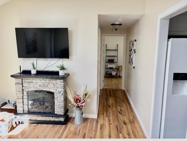 living room with a stone fireplace, wood finished floors, and baseboards