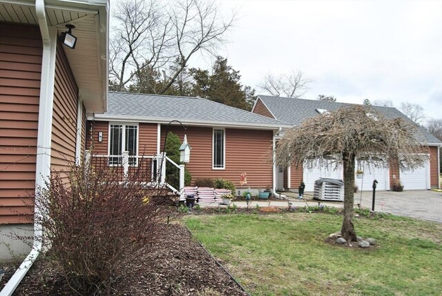 view of front of property with aphalt driveway, roof with shingles, central air condition unit, a front yard, and a garage