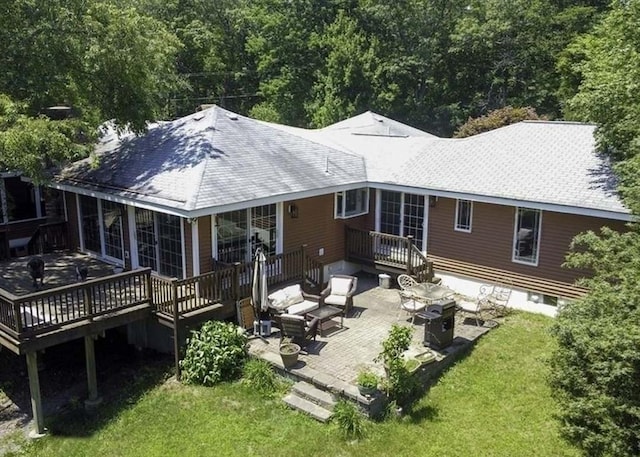 back of property with a deck, a yard, a patio, and a shingled roof