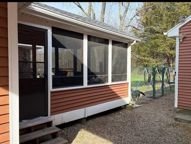 view of side of home with fence, roof with shingles, entry steps, and a sunroom
