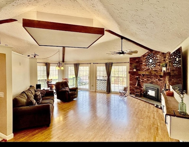 living area featuring a brick fireplace, ceiling fan, light wood-type flooring, a textured ceiling, and lofted ceiling