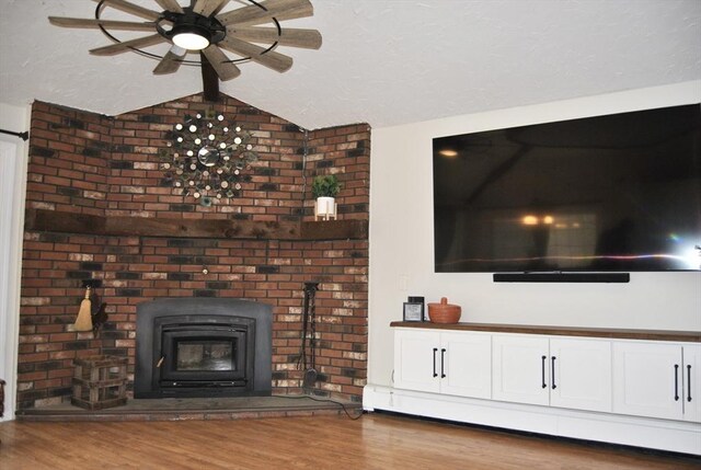 unfurnished living room with a textured ceiling, ceiling fan, vaulted ceiling, and wood finished floors