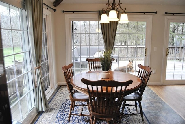dining space featuring a chandelier, baseboards, and wood finished floors