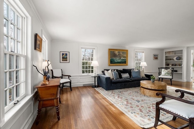 living room with built in shelves, crown molding, and hardwood / wood-style floors