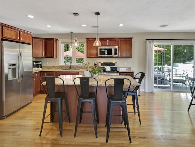119 Esten Rd, Stoughton, MA 02072 - kitchen featuring stainless steel appliances, a sink, light wood finished floors, a kitchen breakfast bar, and light stone counters