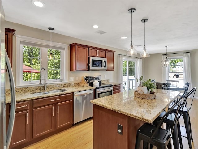119 Esten Rd, Stoughton, MA 02072 - kitchen with appliances with stainless steel finishes, a sink, light wood-style floors, a breakfast bar area, and light stone counters