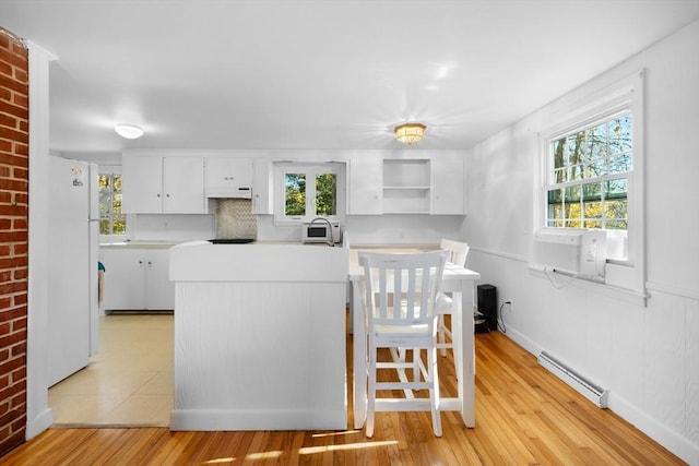 kitchen with cooling unit, a baseboard heating unit, white refrigerator, light hardwood / wood-style flooring, and white cabinetry