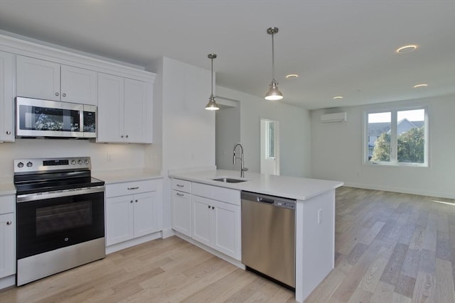 kitchen featuring sink, white cabinetry, stainless steel appliances, decorative light fixtures, and kitchen peninsula