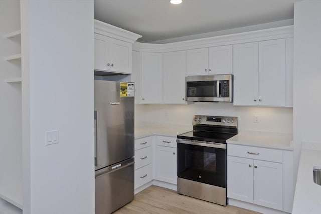 kitchen featuring white cabinets, light wood-type flooring, and appliances with stainless steel finishes