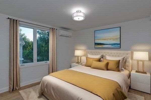 bedroom with a wall mounted AC and light hardwood / wood-style flooring