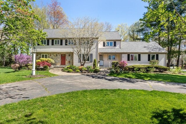 view of front facade with stone siding and a front lawn
