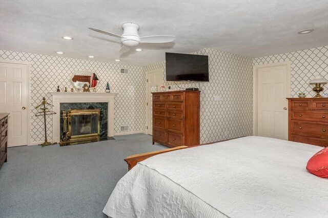 carpeted bedroom with ceiling fan, a premium fireplace, recessed lighting, wallpapered walls, and visible vents