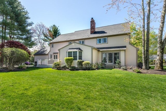 back of property featuring a lawn, a deck, cooling unit, and a chimney