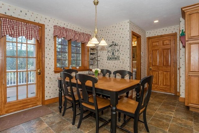 dining space with baseboards, stone finish floor, and wallpapered walls