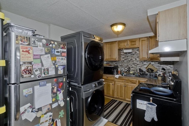 kitchen with sink, stainless steel fridge, electric stove, stacked washing maching and dryer, and backsplash