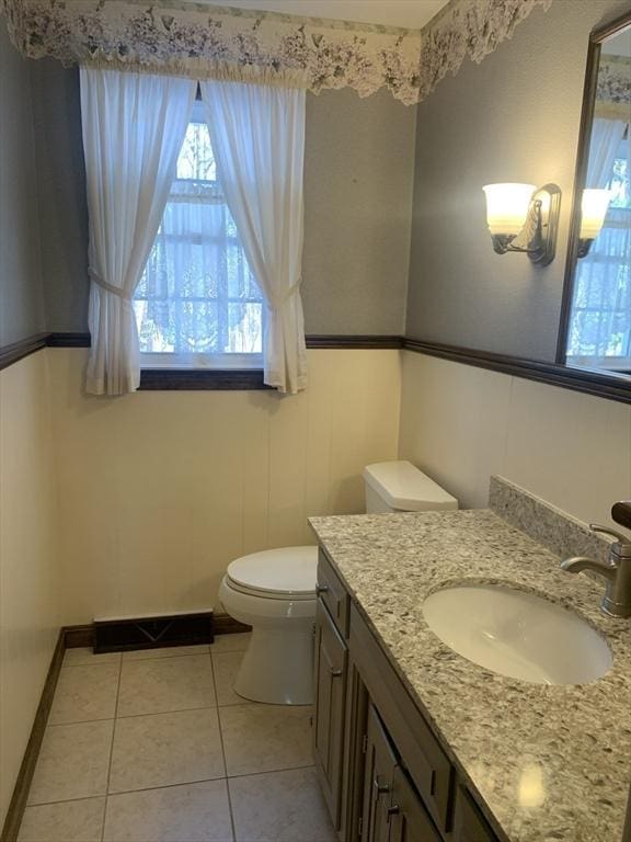 half bath featuring visible vents, toilet, vanity, tile patterned flooring, and baseboards