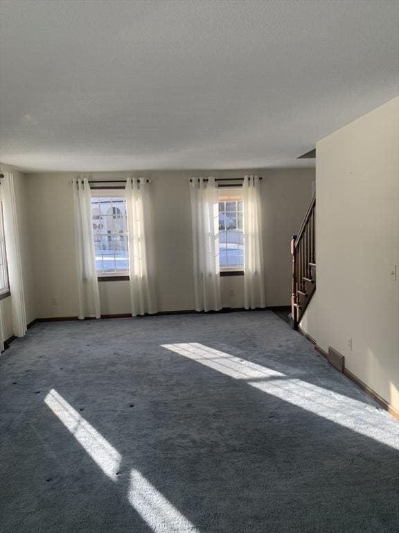 carpeted spare room featuring stairs and baseboards