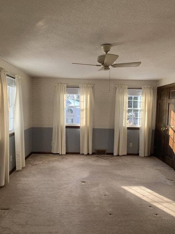 unfurnished room featuring light carpet, wallpapered walls, a ceiling fan, and a textured ceiling