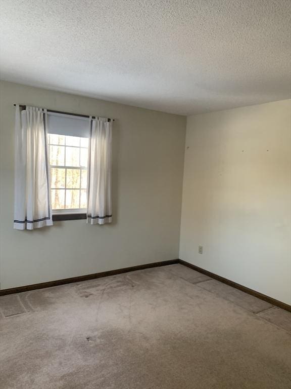 empty room featuring carpet, baseboards, and a textured ceiling