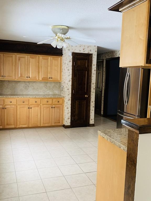 kitchen featuring freestanding refrigerator, light countertops, ceiling fan, and wallpapered walls