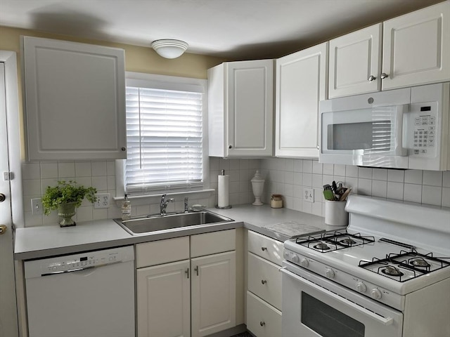 kitchen with tasteful backsplash, white appliances, white cabinets, and a sink