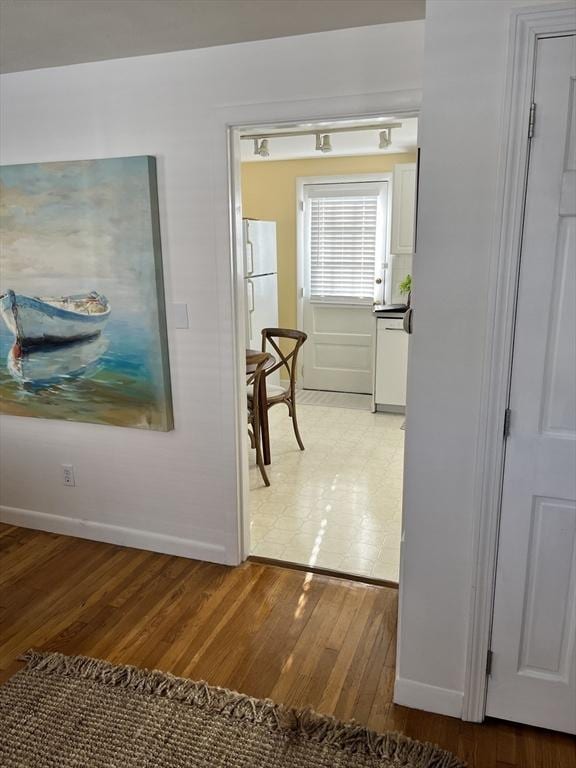 hall with light wood-type flooring and baseboards