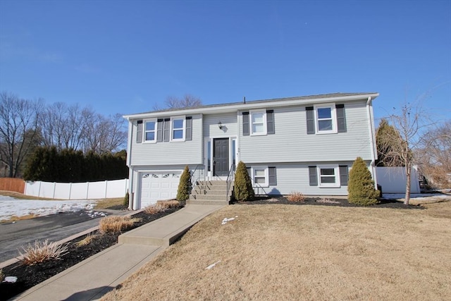 split foyer home featuring an attached garage and fence