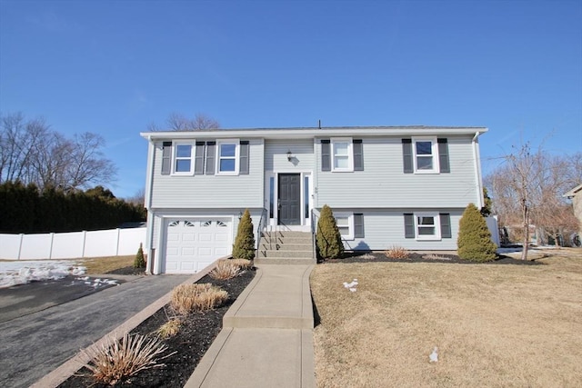 bi-level home featuring aphalt driveway, an attached garage, and fence