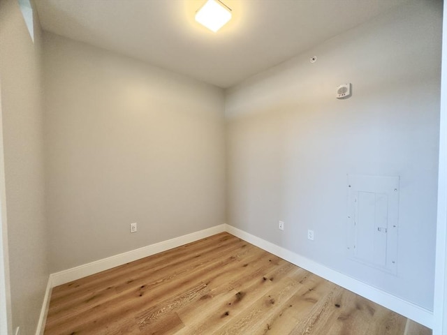 empty room with electric panel and hardwood / wood-style flooring