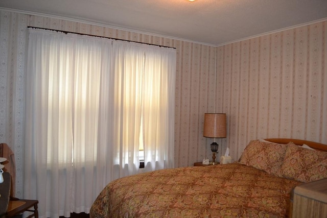 bedroom featuring crown molding and wallpapered walls
