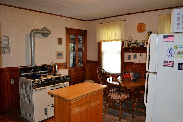 kitchen with wooden walls, wainscoting, ornamental molding, and white appliances