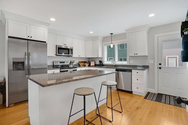 111 Union St Unit 8, Westfield, MA 01085 - kitchen featuring stainless steel appliances, white cabinetry, a breakfast bar, a center island, and light wood-style flooring