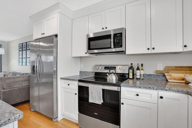 111 Union St Unit 8, Westfield, MA 01085 - kitchen with stainless steel appliances, open floor plan, white cabinets, light wood finished floors, and stone counters