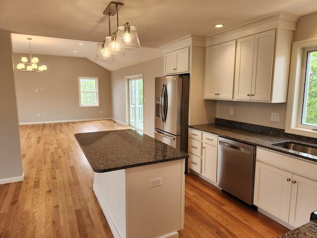 56 Kelly Ln, Lynn, MA 01904 - kitchen with appliances with stainless steel finishes, vaulted ceiling, healthy amount of natural light, dark stone counters, and light wood-style flooring