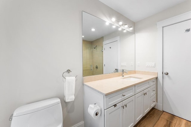 bathroom with tiled shower, vanity, toilet, and wood finished floors