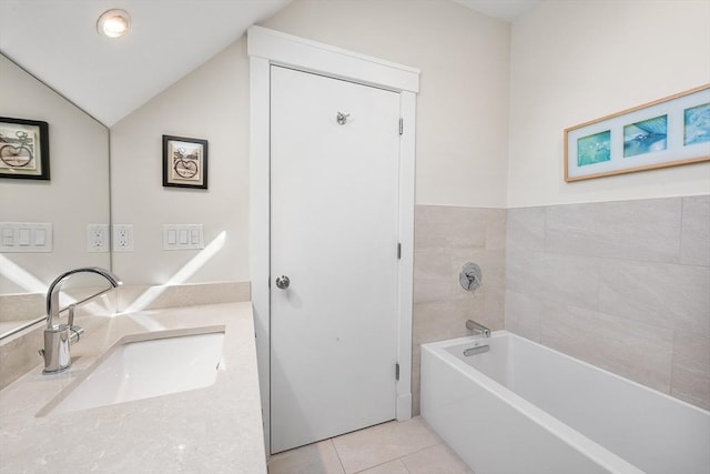 bathroom with vaulted ceiling, tile patterned floors, a washtub, and vanity