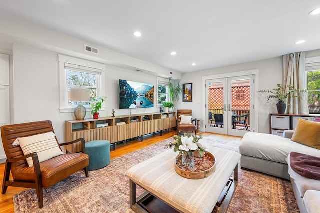 living area with recessed lighting, visible vents, french doors, and wood finished floors